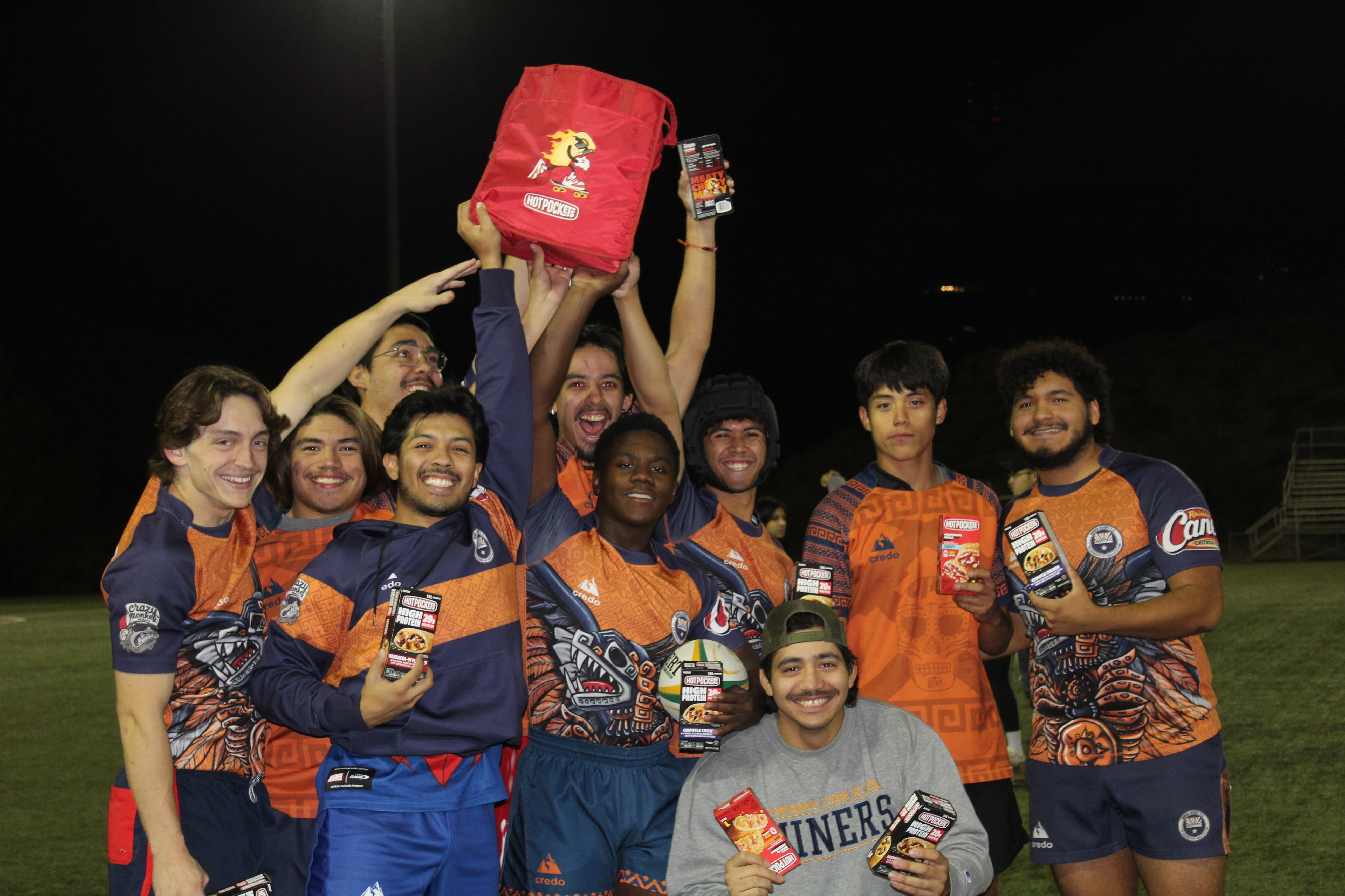 College sports team at night holding unopened Hot Pockets boxes